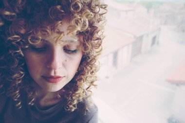 gri duvar zemin üzerine kıvırcık saçlı Genç Sevimli kadın fotoğrafı