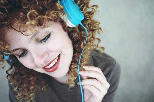 Photo Young Cute Woman Curly Hair Blue Headphones Grey Wall — Stock Photo, Image