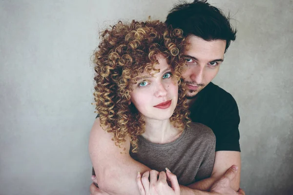 adam gri duvar zemin üzerine kıvırcık saçlı sarılmak ile genç Sevimli kadın fotoğrafı