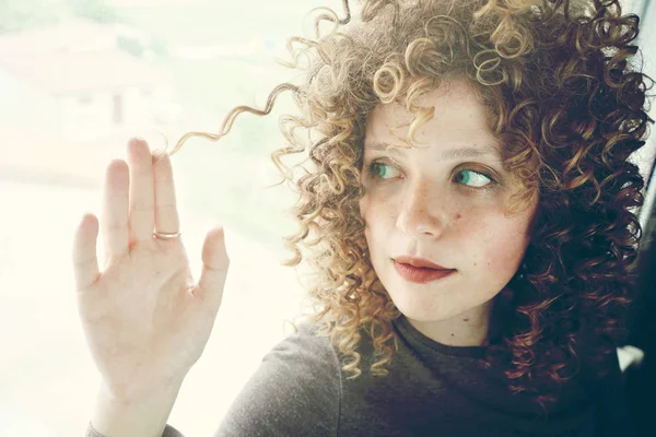 gri duvar zemin üzerine kıvırcık saçlı Genç Sevimli kadın fotoğrafı