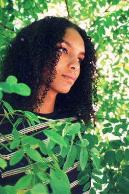 Yeşil yaprakları üzerinde arka plan açık havada poz genç güzel Afrikalı kadın portresi