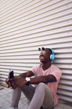 Yakışıklı delikanlı onun smartphone ile müzik dinlemek komik güneş gözlüğü takıyor