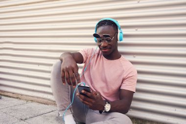 Yakışıklı delikanlı onun smartphone ile müzik dinlemek komik güneş gözlüğü takıyor
