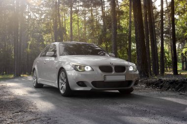 Kiev, Ukrayna - 9 Eylül 2018. BMW E60 orman yolu üzerinde. Işıklar açık ormandaki bir araba