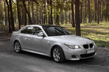 Kiev, Ukrayna - 9 Eylül 2018. BMW E60 orman yolu üzerinde. Işıklar açık ormandaki bir araba