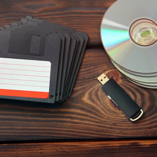 Floppy disks, USB flash drive and disks on a wooden background