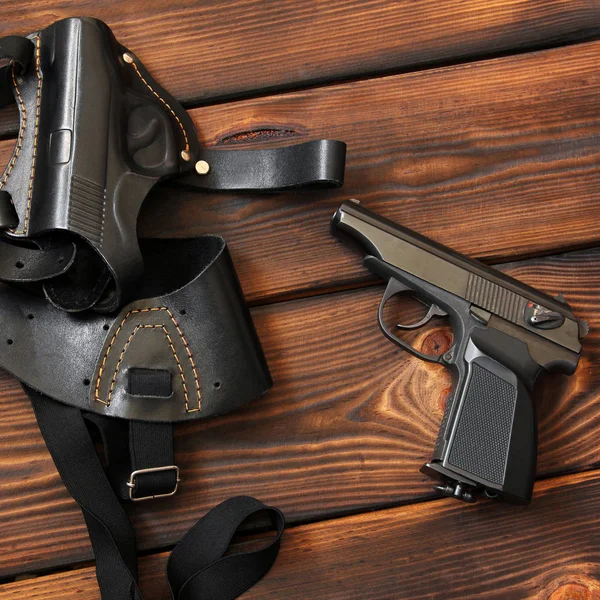 La pistola y la funda para una pistola sobre fondo de madera. Arma. — Foto de Stock