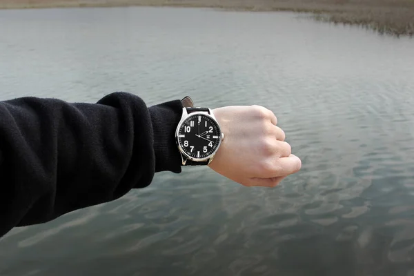 The clock on the hand on the background of water — Stock Photo, Image