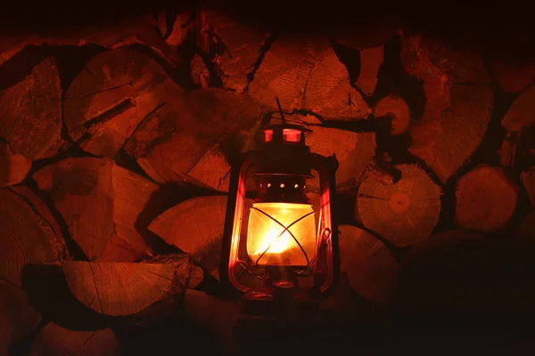 Petroleumlampe im Dunkeln. Petroleumlampe auf dem Hintergrund von Holzstämmen — Stockfoto