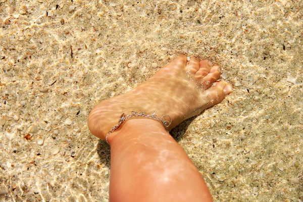 Красивая женская нога в воде. Браслет на ноге — стоковое фото