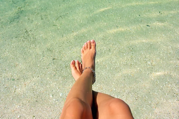 Красивые женские ноги на фоне воды. Браслет на... — стоковое фото