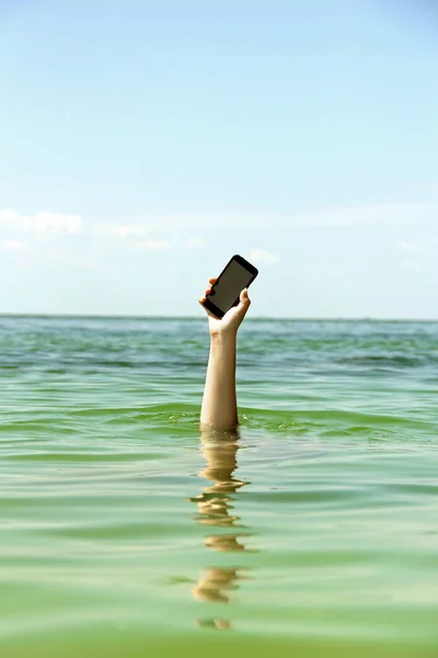 Рука с телефоном в море. Отдых на море . — стоковое фото
