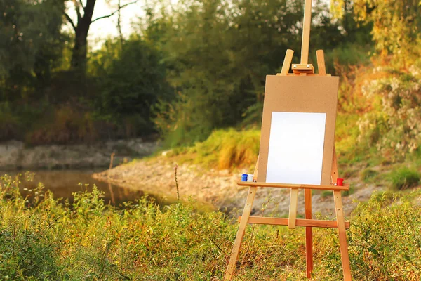 Easel with paints on a background of nature — Stock Photo, Image