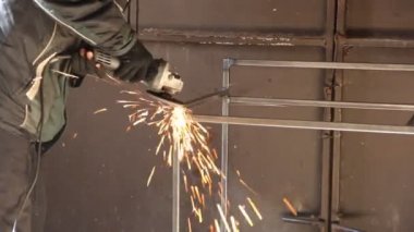 Açı öğütücüyle çalışan bir adam. Öğütücüden çıkan kıvılcımlar. Metal öğütme işlemi