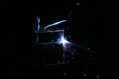 Kaynak kaynaklarından kıvılcımlar. Bir adam metali kaynak yapacak. Kaynakçıların işyeri. Garaj kaynakçısı