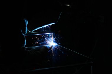 Kaynak kaynaklarından kıvılcımlar. Bir adam metali kaynak yapacak. Kaynakçıların işyeri. Garaj kaynakçısı