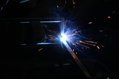 Kaynak kaynaklarından kıvılcımlar. Bir adam metali kaynak yapacak. Kaynakçıların işyeri. Garaj kaynakçısı
