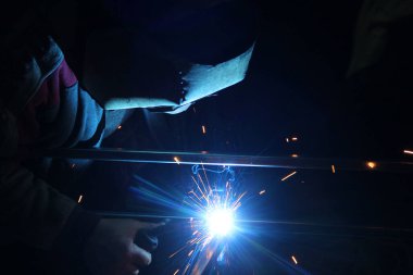 Kaynak kaynaklarından kıvılcımlar. Bir adam metali kaynak yapacak. Kaynakçıların işyeri. Garaj kaynakçısı