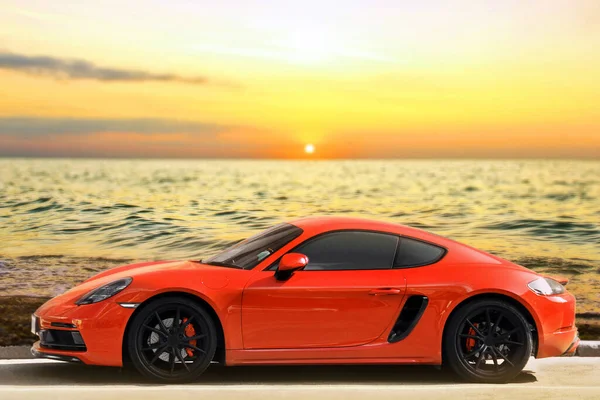 日没の背景に赤いスポーツカー スーパーカーと海 — ストック写真