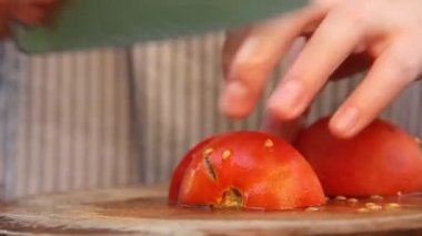 Domatesi yakın plan dilimliyorum. Kız domatesleri kesiyor. Domates ve bıçak. Yemek pişirmek. Malzemelerin hazırlanması.