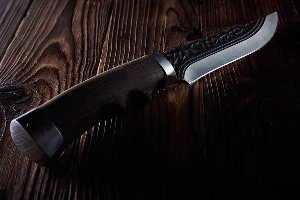 Cuchillo de caza viejo acostado en una mesa de madera tallada en la oscuridad — Foto de Stock