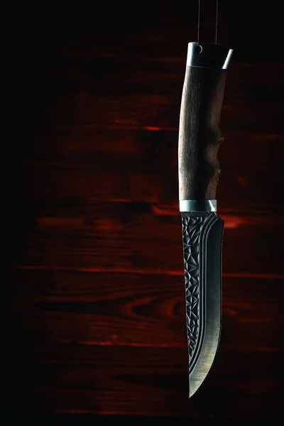 Cuchillo de caza viejo acostado en una mesa de madera tallada en la oscuridad —  Fotos de Stock