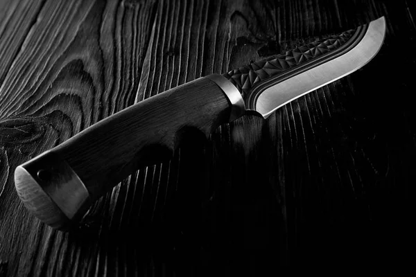 Karanlıkta oyulmuş ahşap bir masanın üzerinde yatan eski av bıçağı — Stok fotoğraf