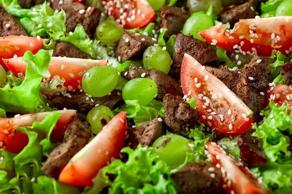 Ahşap masada tavuk karaciğeri ve üzüm ile sıcak salata — Stok fotoğraf
