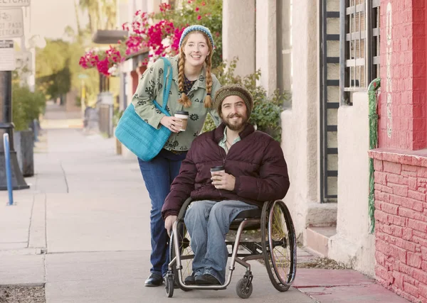 Woman with friend in wheelchair holding coffee