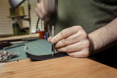 Deri uzatma kablosuna bir perçin için delik açma el yakın çekim