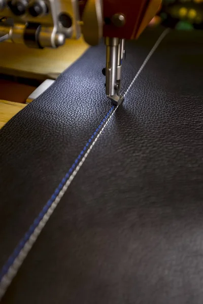 Leather on industrial sewing machine showing white and blue stitches