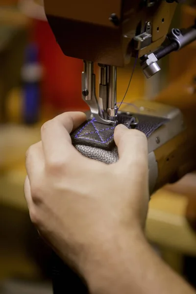 Vertical shot of making a box stitch seam pattern on black leather