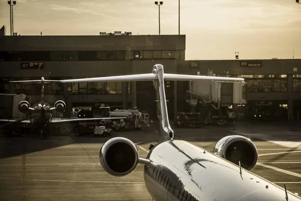 Jet parked at gate of a busy airport in the afternoon