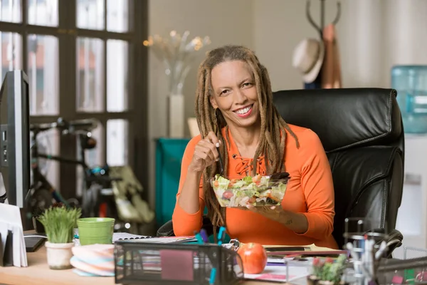 Stylová žena s drealocks pojídáním zdravého oběda u jejího stolu — Stock fotografie