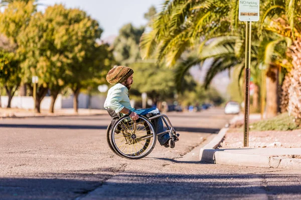 Человек в инвалидной коляске приближается к бордюру города — стоковое фото