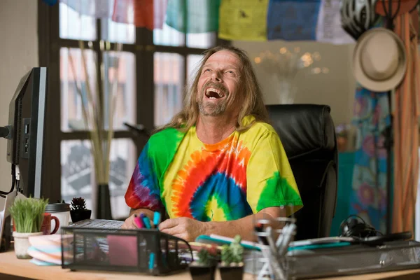 Homem rindo com cabelos longos em um escritório colorido — Fotografia de Stock
