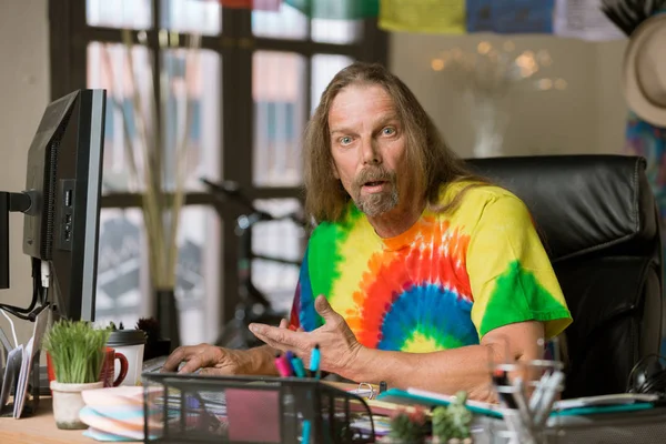 Homem surpreso com cabelos longos em um escritório colorido — Fotografia de Stock