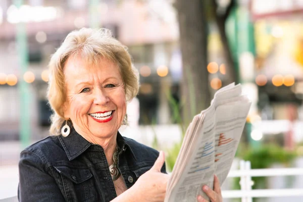 Счастливая женщина, реагирующая на газетную историю — стоковое фото