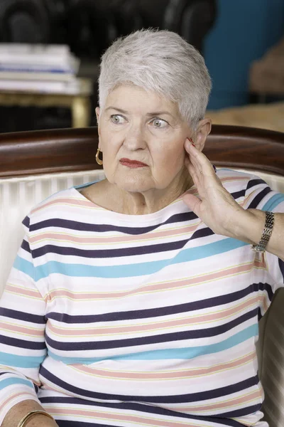 Worried senior woman on couch at home