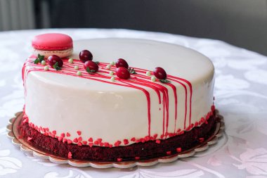 Kırmızı meyveler ve macaron tarafından dekore edilmiş lezzetli beyaz ev yapımı kek. Modern fotoğraf.