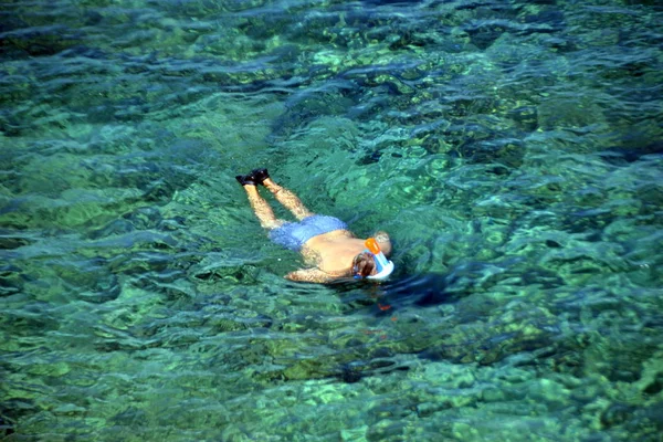 Мужчина плавает под водой в спасательной рубашке и маске для подводного плавания на острове Бенидорм, Испания — стоковое фото