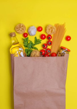 Zeytin yağı, makarna, tagliatelle, zeytin, kiraz domatesleri, sarı arka planda sarımsak.