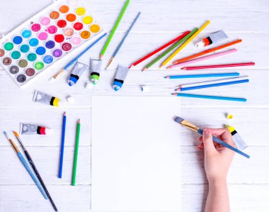 Resim ve çizim için bir model. Kalem fırçasını tutan ve beyaz kağıda çizen eller. Yukarıdan görüntüle.