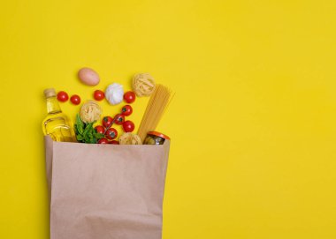 Zeytin yağı, makarna, tagliatelle, zeytin, yumurta, kiraz domatesleri, sarı arka planda bir kesede sarımsak.