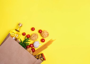 Zeytin yağı, makarna, tagliatelle, zeytin, yumurta, kiraz domatesleri, sarı arka planda bir kesede sarımsak.