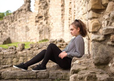 Bir şatonun yıkıntıları arasında oturan ve hayal kuran bir kız