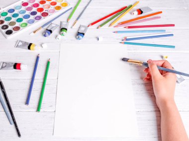 Resim ve çizim için bir model. Kalem fırçasını tutan ve beyaz kağıda çizen eller. Yukarıdan görüntüle.
