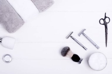 Ustura, fırça, balsam, parfüm, havlu ve makas ahşap arka planda.