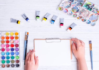 Resim ve çizim için bir model. Kalem fırçasını tutan ve beyaz kağıda çizen eller. Yukarıdan görüntüle.