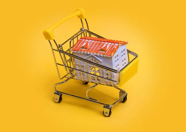 Carrinho Compras Com Uma Casa Brinquedo Fundo Amarelo — Fotografia de Stock